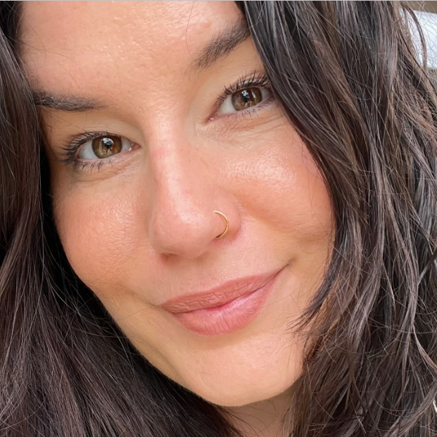 Kundinnen Feedback Kinderwunsch Coaching Schrörs Porträt einer Frau mit langen, lockigen, braunen Haaren und sanftem Lächeln.